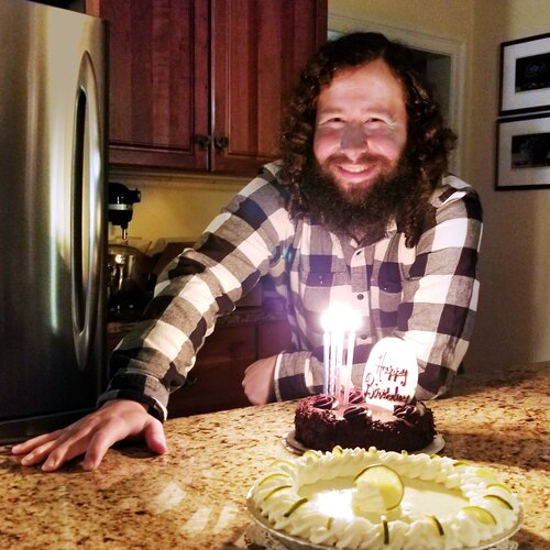 Nick in front of a cake and candles on his 27th birthday