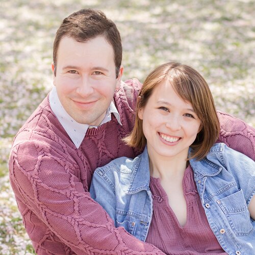 Julia and Nick sitting in the grass holding
                      each other